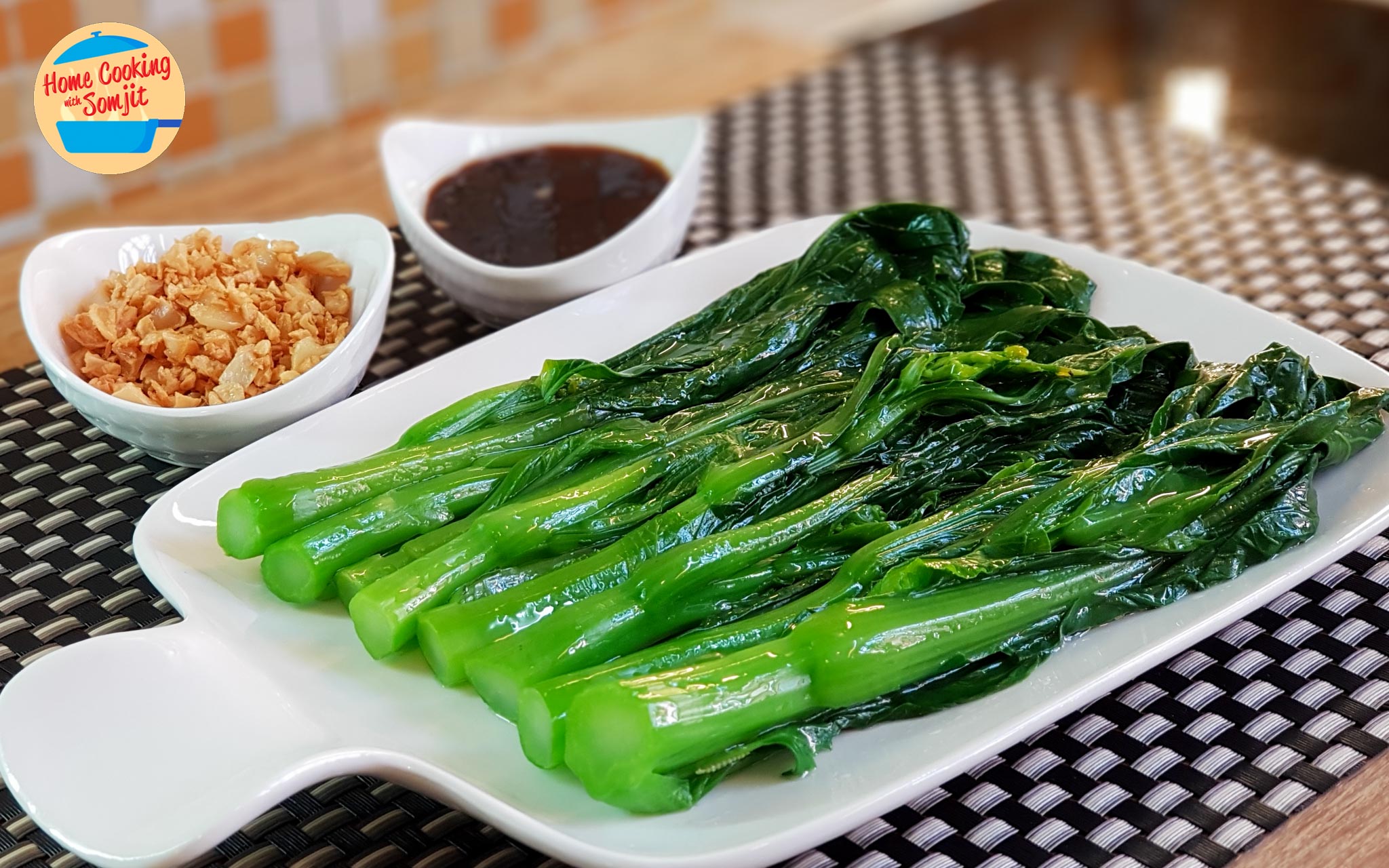 Blanched choy sum flanked by the cooked sauce and fried garlic.