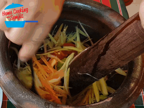 Mixing Papaya with Sauce Using a spoon and pestle, the shredded papaya strips are thoroughly mixed in the mortar.